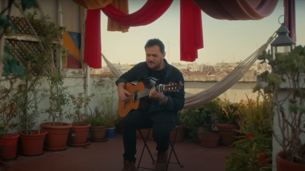 portada video ismael serrano - me amo. Tocando la guitarra sentado en una terraza